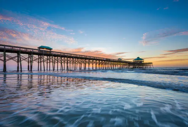 Waves in the Atlantic Ocean and the pier at sunrise, in Folly Beach, South Carolina