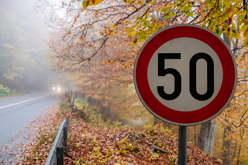 Restriction 50 kilometres in the autumn forest on highway in the mountains.