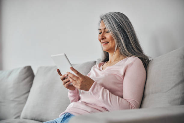istock Charming elegant female looking to the screen modern device isolated on grey background 1284155018