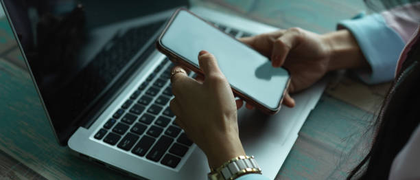 istock Female hands using smartphone while working with laptop in office room 1284155959