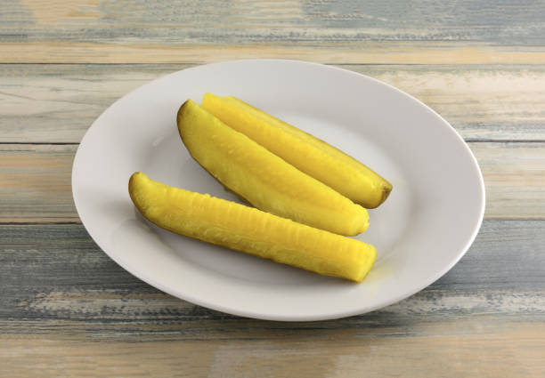 Three dill pickle spears Three dill pickle spears on small white snack plate on table dill pickle stock pictures, royalty-free photos & images