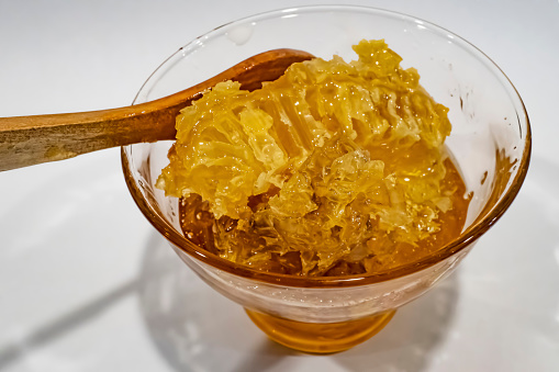 honeycomb honey in glass bowl with wooden spoon