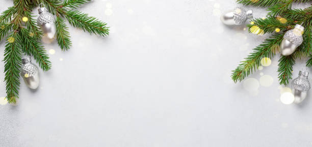 istock Christmas horizontal banner. Fir tree branches with silver oaks on stone background. Top view. Copy space. Bokeh effect 1284164524