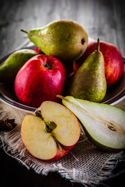 Pears and apples with cloves on wooden table