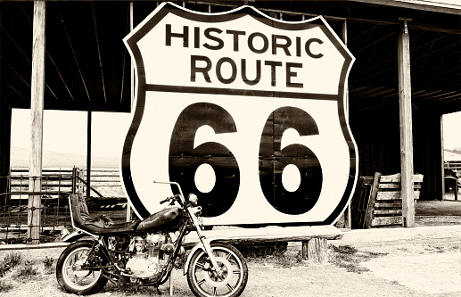 Vintage Motorcycle in front of an abandoned shed, Route 66 near to the vintage Frontier motel, Truxton, Mohave county, Arizona, USA. Sepia toned.