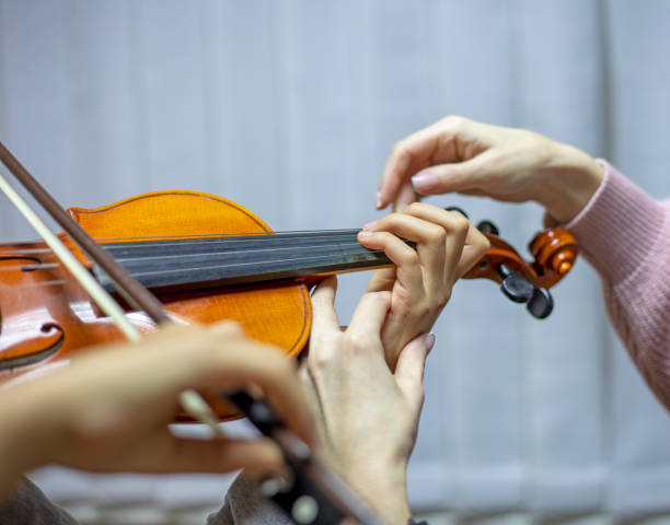 istock helping the teacher to keep his hand on the violin correctly, placing children's hands when playing the violin 1284186963