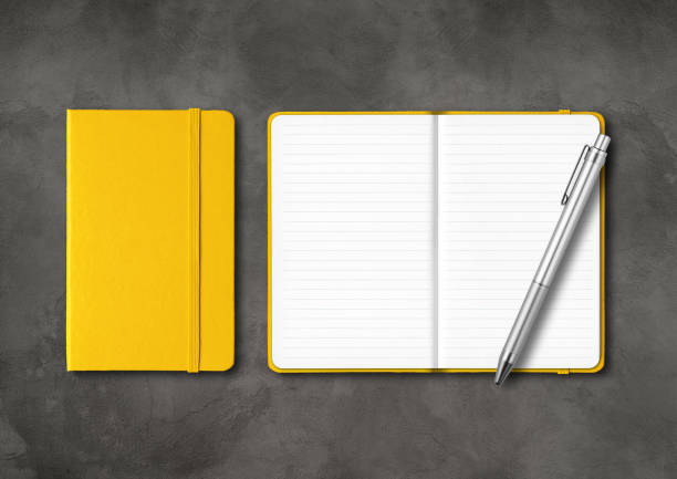 istock Yellow closed and open lined notebooks with a pen on dark concrete background 1284187185