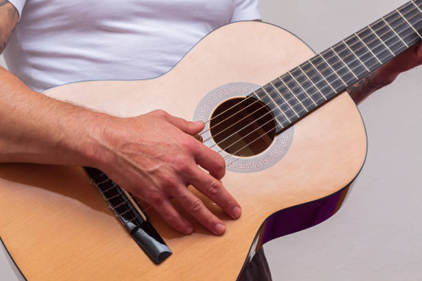 istock Acoustic guitar resting on a white background with copy space. a person's hand holding it 1284188793