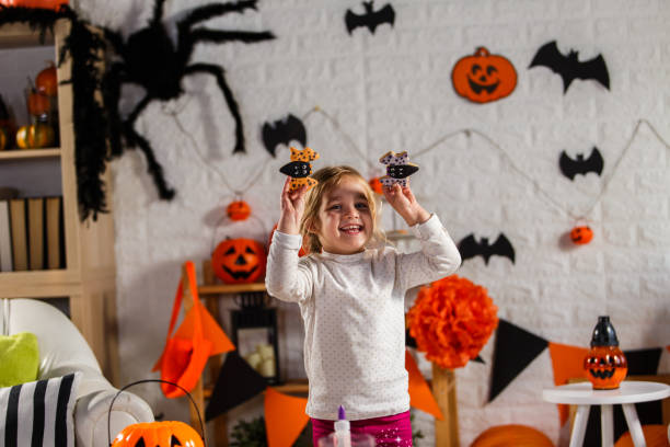istock Happy little girl with two bat shaped cookies 1284190201