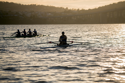 Hobart, Tasmania, Australia, March 3, 2016: Early morning view on the river Derwent in Hobart of a a single sculler and coxless four rowers training