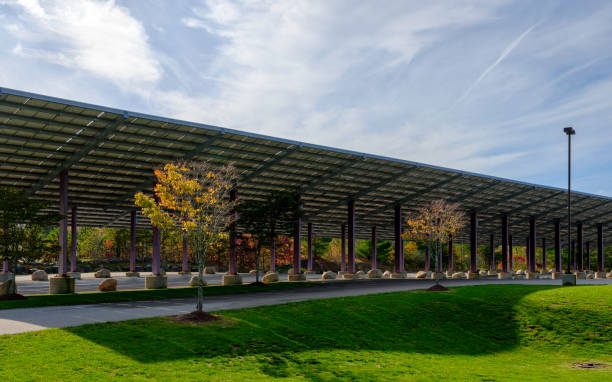 Solar Panels Covering the Parking Lot over Green Garden with Zen-like Rocks Archeterual landscape with energy-saving solar rooftop and tranquil garden with minimalistic design at the Technological Park on Cape Cod triangular solar panels stock pictures, royalty-free photos & images