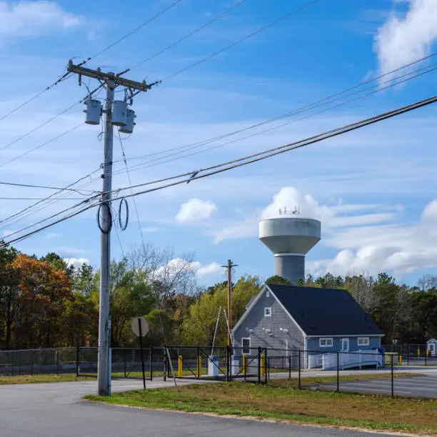 Photo of Electrical pole and cables with water tower and clouds on the backgrounds
