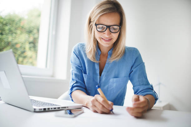 business woman with blue shirt and glasses is working in office stock photo