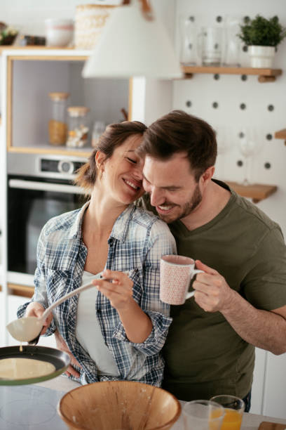 Husband and wife making pancakes at home