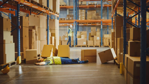 istock Shot of a Warehouse Worker Has Work Related Accident. He is Falling Down BeforeTrying to Pick Up Heavy Cardboard Box from the Shelf. Hard Injury at Work. 1284193393