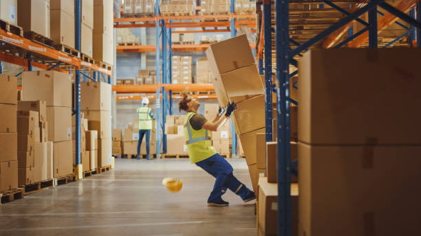 la ripresa di un lavoratore warehouse ha un infortunio correlato al lavoro. sta cadendo prima dicerare di raccogliere la scatola di cartone pesante dallo scaffale. infortunio al lavoro. - ripostiglio luogo di lavoro foto e immagini stock