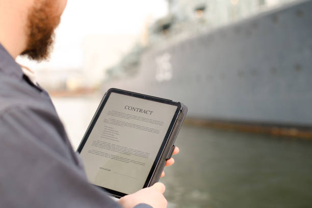 istock Marine engineer reading contract on tablet near vessel in background 1284193763
