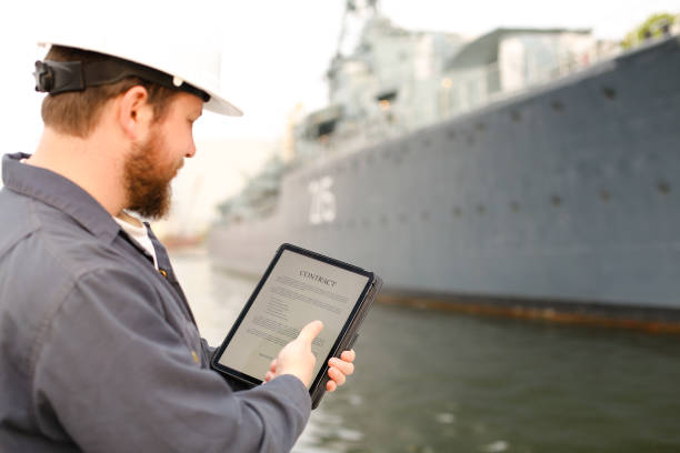 istock Captain in helmet reading contract on tablet near vessel in background 1284193780