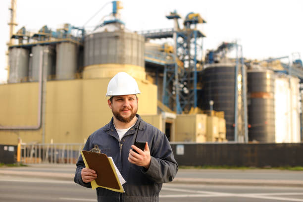 istock Engineer holding walkie talkie and notes, factory in background 1284193802