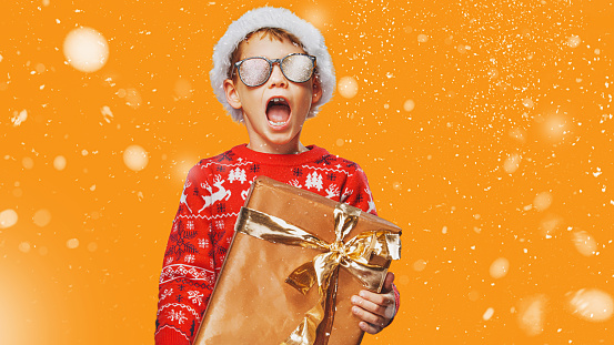 Boy at Christmas with the gift against a red background. Cry of happiness