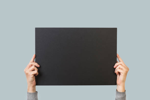 istock Woman hands holding a blank black paper 1284195605