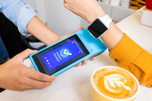 mobile payment concept - close up of use credit card to pay the bills by smartwatch