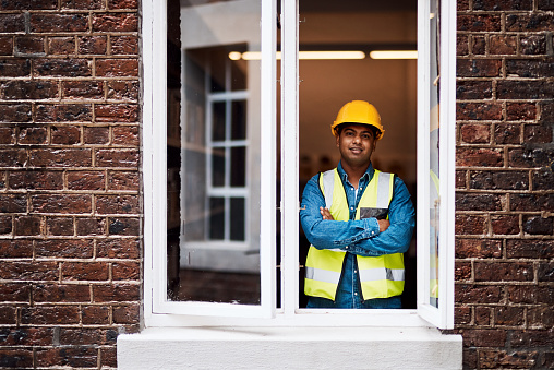 Shot of a young engineer standing in the window of a construction site