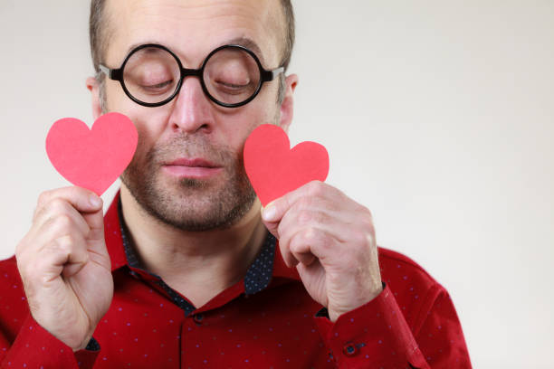 Adult serious man holding two red hearts. Romance love valentines day concept.