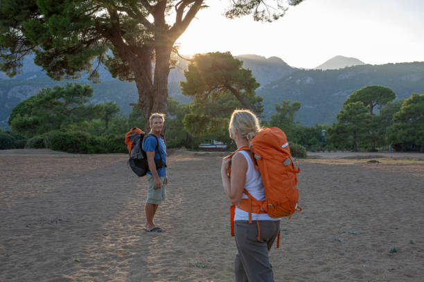 caminhantes caminham pela praia pela manhã - sunrise beach couple hiking - fotografias e filmes do acervo