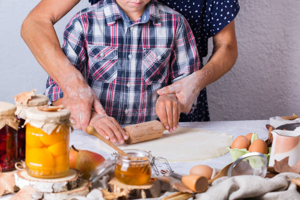 孫料理、生地をこね、台所で焼く祖母 - grandmother senior adult family domestic kitchen ストックフォトと画像