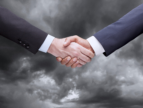 Business Handshake over the storm clouds
