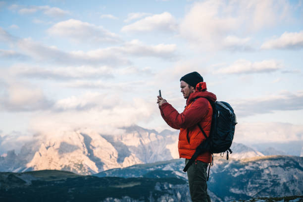 istock Male hiker uses cell phone on mountain ridge crest 1284202850