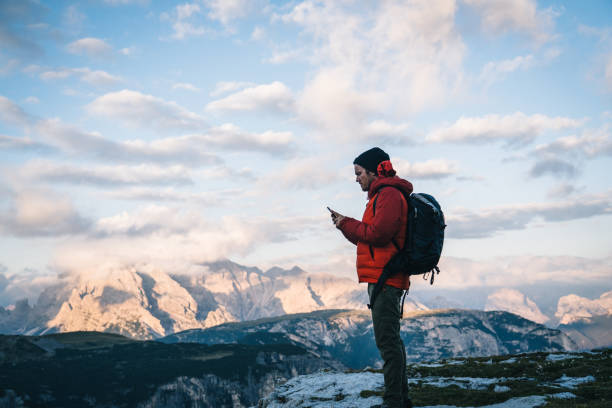 istock Male hiker uses cell phone on mountain ridge crest 1284202866