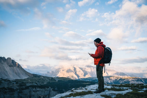 istock Male hiker uses cell phone on mountain ridge crest 1284202876