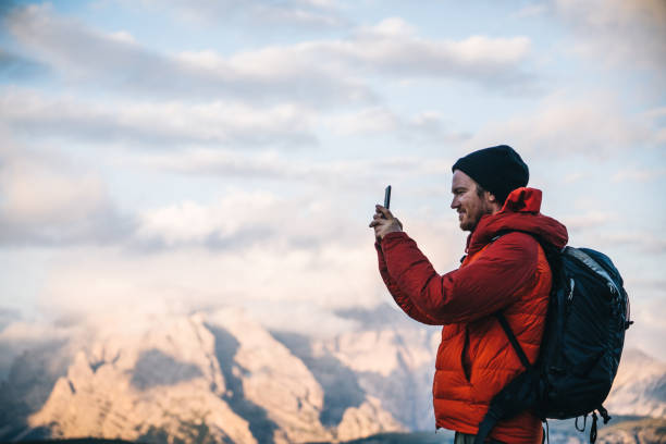 istock Male hiker uses cell phone on mountain ridge crest 1284203041