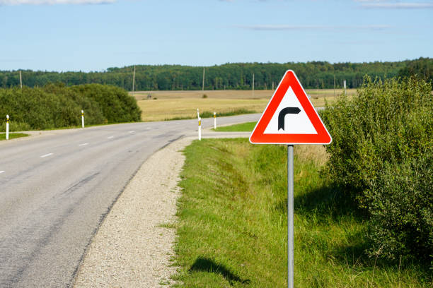 señal de carretera de advertencia gire a la derecha en el fondo de una carretera de asfalto en una zona rural - turning right fotografías e imágenes de stock