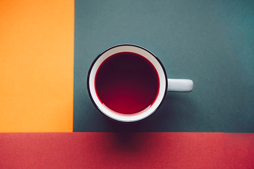 Abstract square background with a cup of Hibiscus red tea.Dark green, yellow and terracotta.
