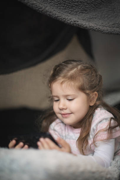 istock Young girl hiding under the covers using mobile phone 1284216919