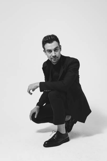 Studio portrait of a young man in a black blazer against plain studio background