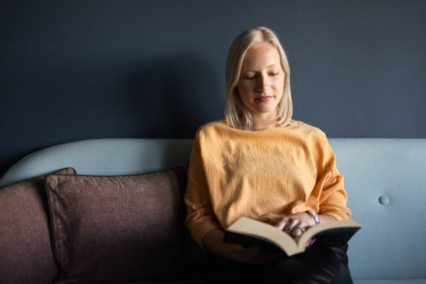 istock Woman reading book on sofa 1284222777