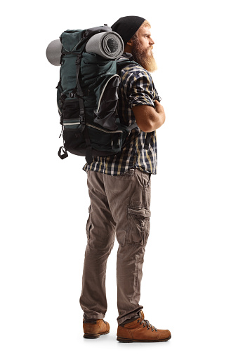 Full length shot of a young bearded man with a backpack and hiking equipment isolated on white background