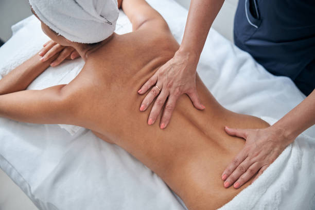 istock Masseur hands massaging young woman back in spa salon 1284223938
