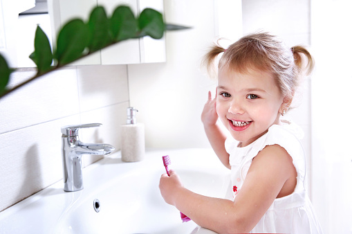 Child cleaning teeth with toothbrush,little girl in bathroom dental hygiene concept.Oral care.