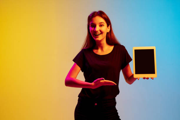 istock Young caucasian woman's portrait on gradient blue-yellow studio background in neon light 1284225112