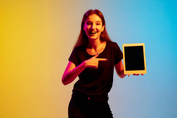 istock Young caucasian woman's portrait on gradient blue-yellow studio background in neon light 1284225117
