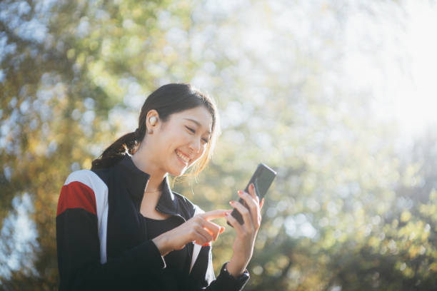 istock Happy Asian young woman using her smartphone in the park 1284225219
