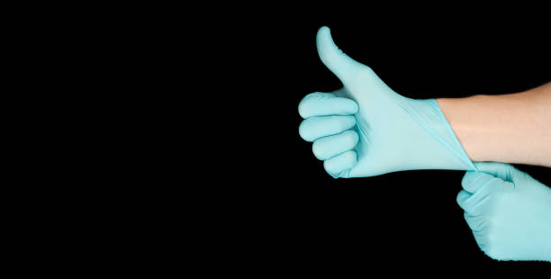 istock Hand in blue glove isolated on black with thumb up. 1284229484