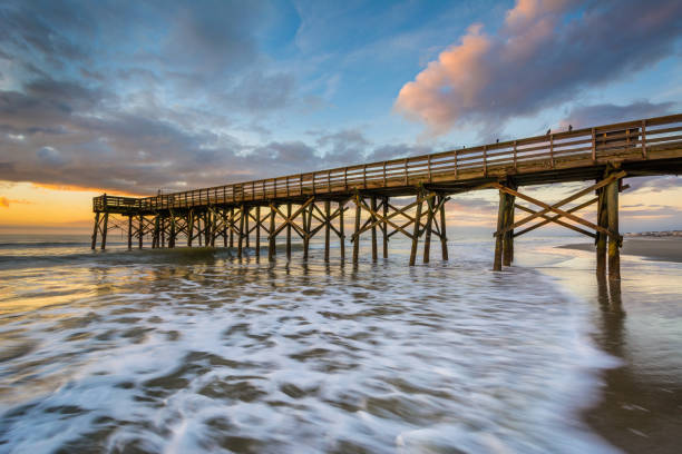 Waves in the Atlantic Ocean and the pier at sunrise, in Isle of Palms, South Carolina stock photo