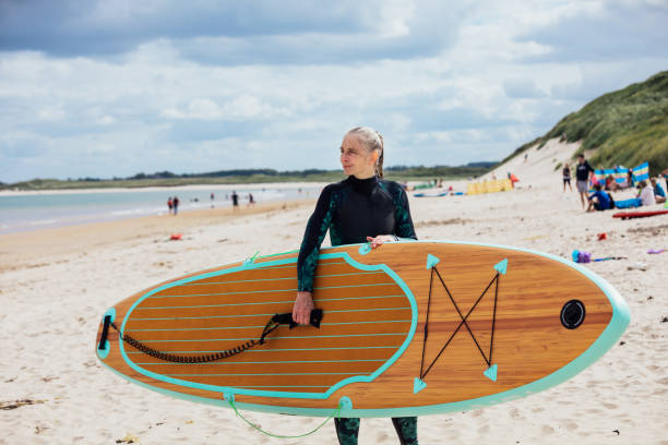 istock Mature Woman Holding a Paddleboard on the Beach 1284234167