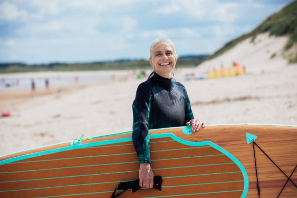 istock Mature Woman Carrying Paddleboard on the Beach 1284234183